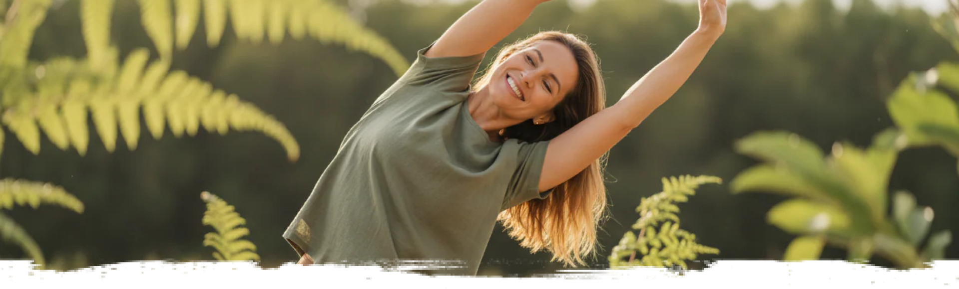 A happy woman in an outdoor setting, smiling and stretching her arms out.
